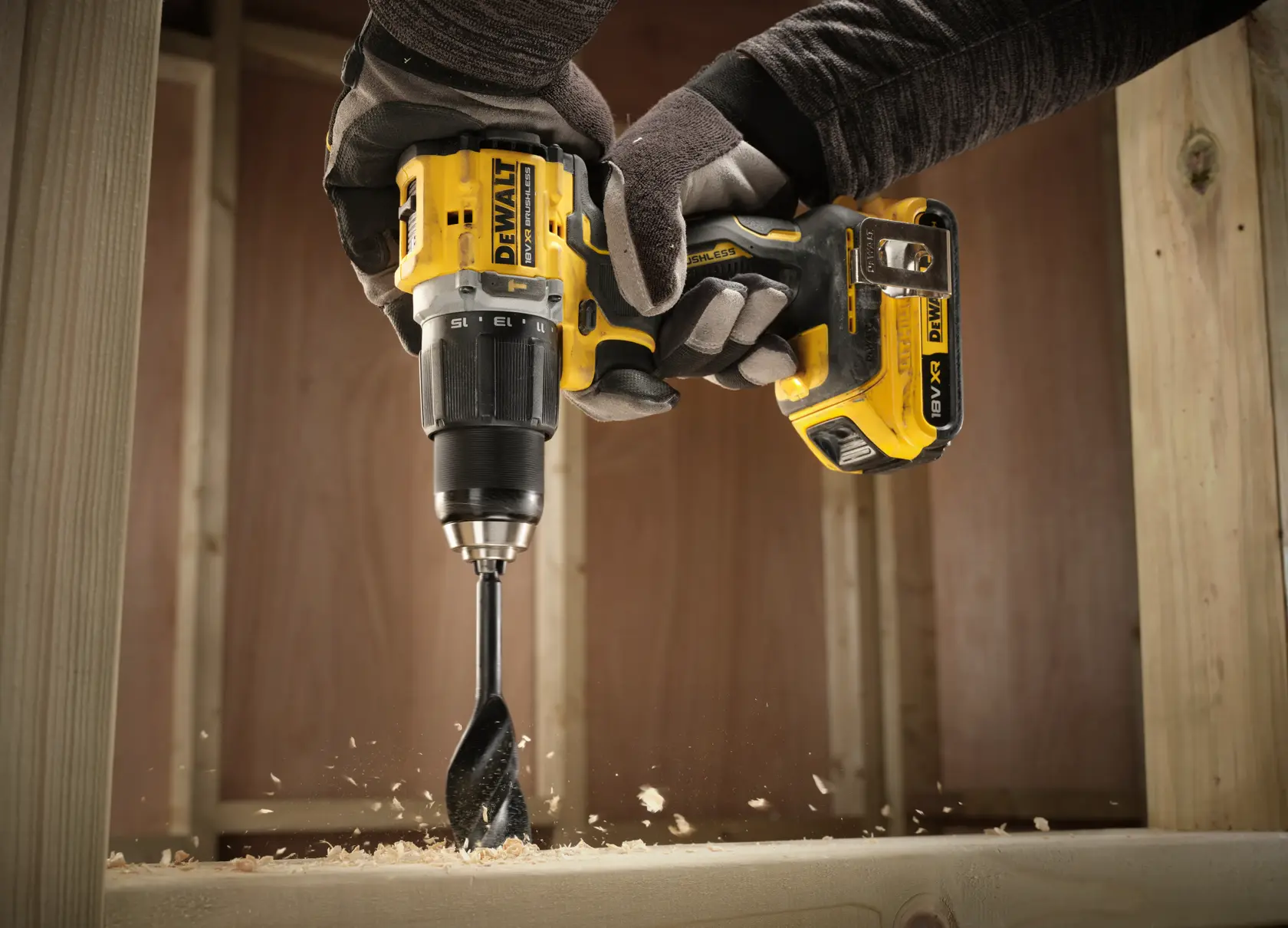 Taladro inalámbrico DEWALT perforando madera, virutas visibles, operario usando guantes.