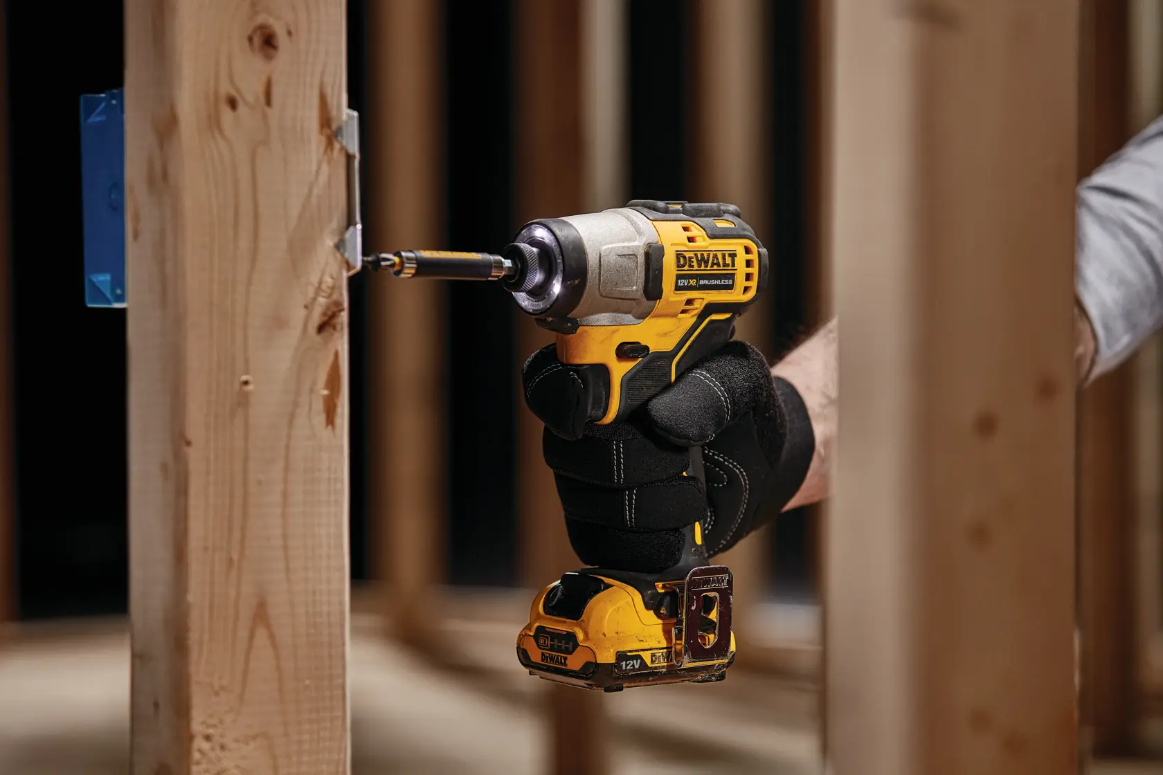 Mano enguantada usa herramienta DEWALT DCF601N para perforar estructura de madera.