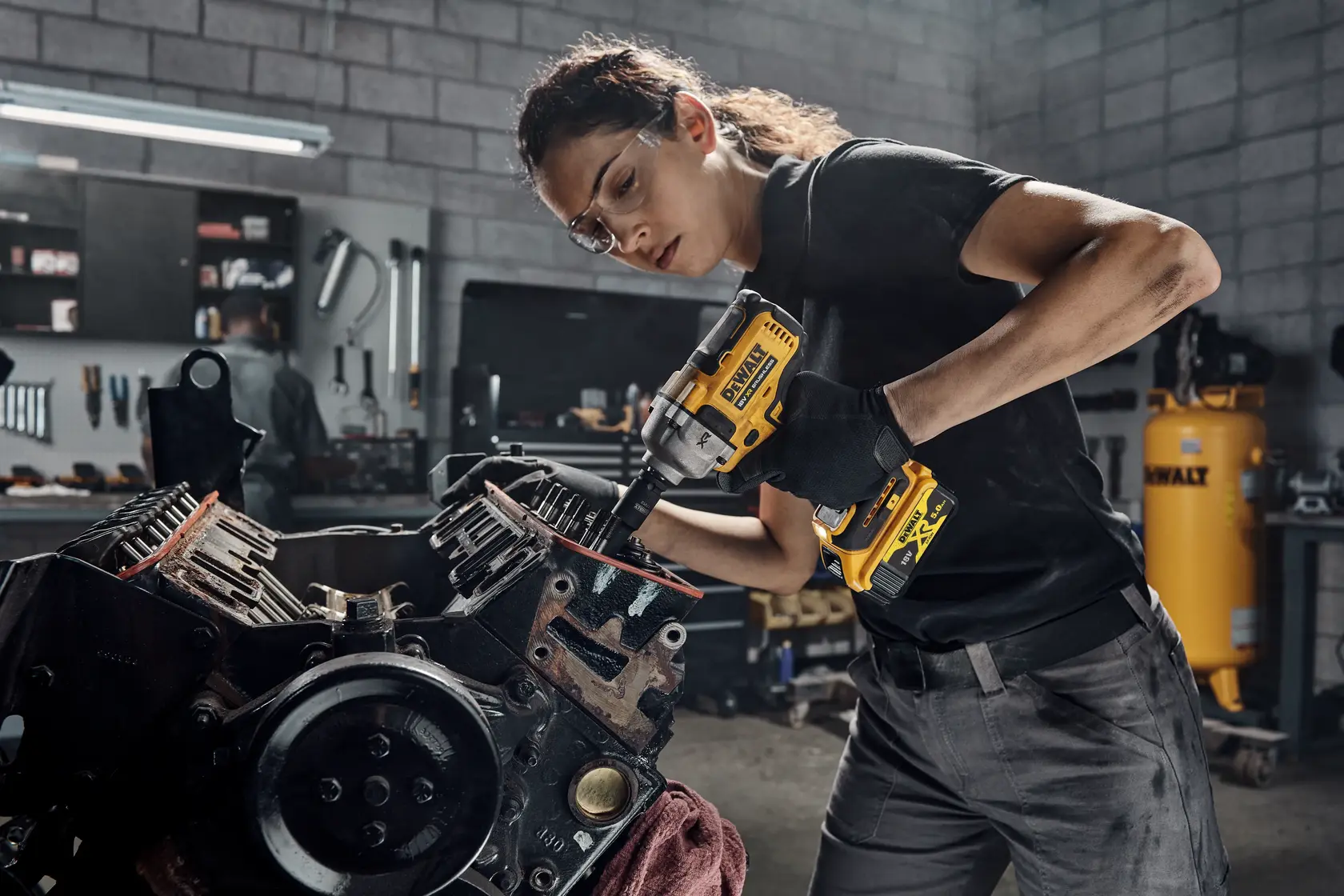 Photo of DEWALT DCF892P2T impact wrench used on engine part in workshop.