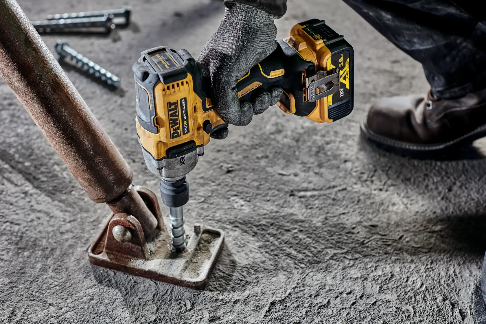 Photo of DEWALT DCF892P2T impact wrench used on metal base, yellow and black tool on concrete floor.