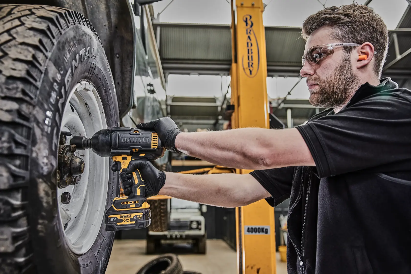 Persona usa avvitatore DEWALT DCF900P2G per stringere i dadi ruota di un veicolo in officina.