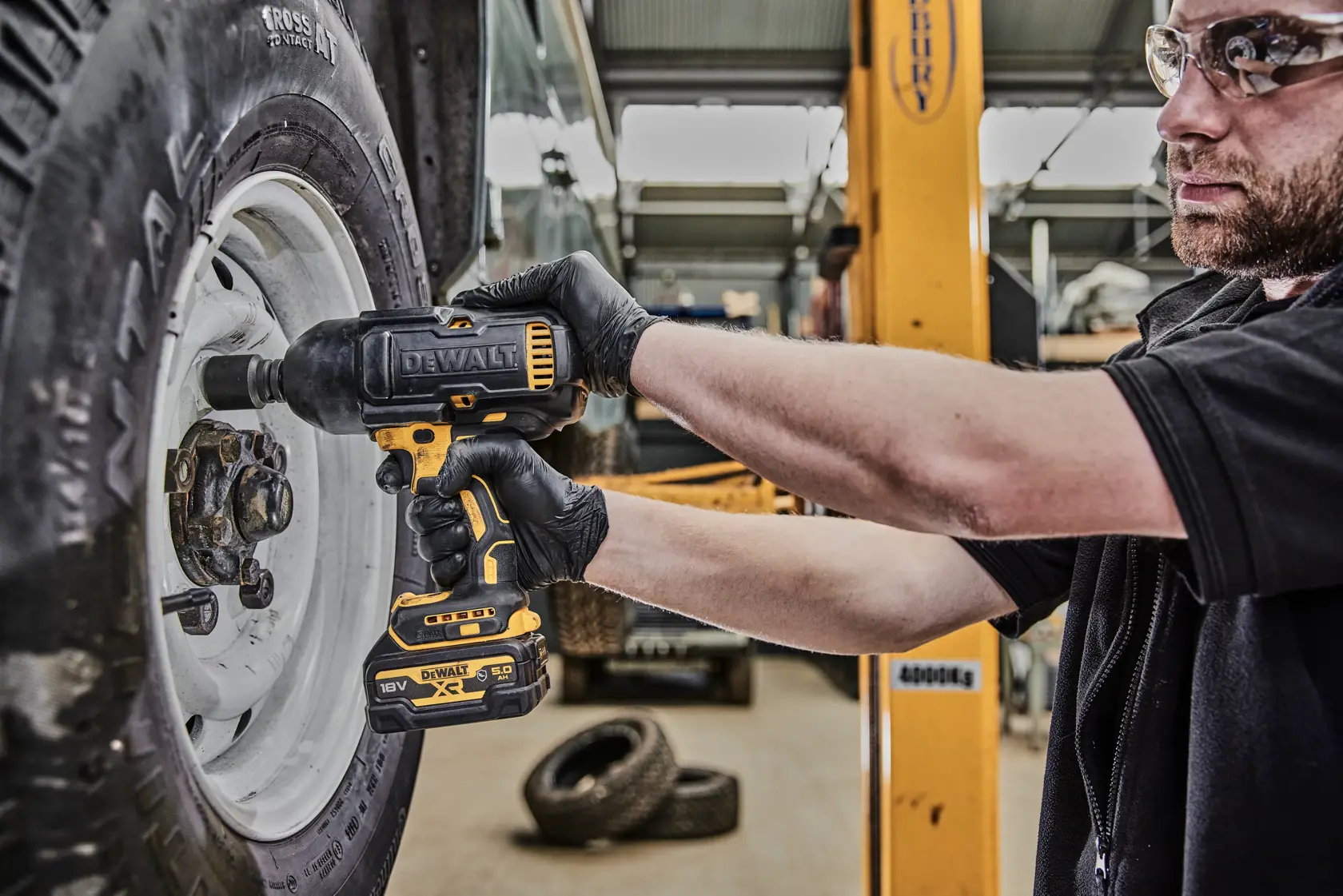 Avvitatore a impulsi DEWALT DCF900P2G usato per serrare un dado ruota in officina.