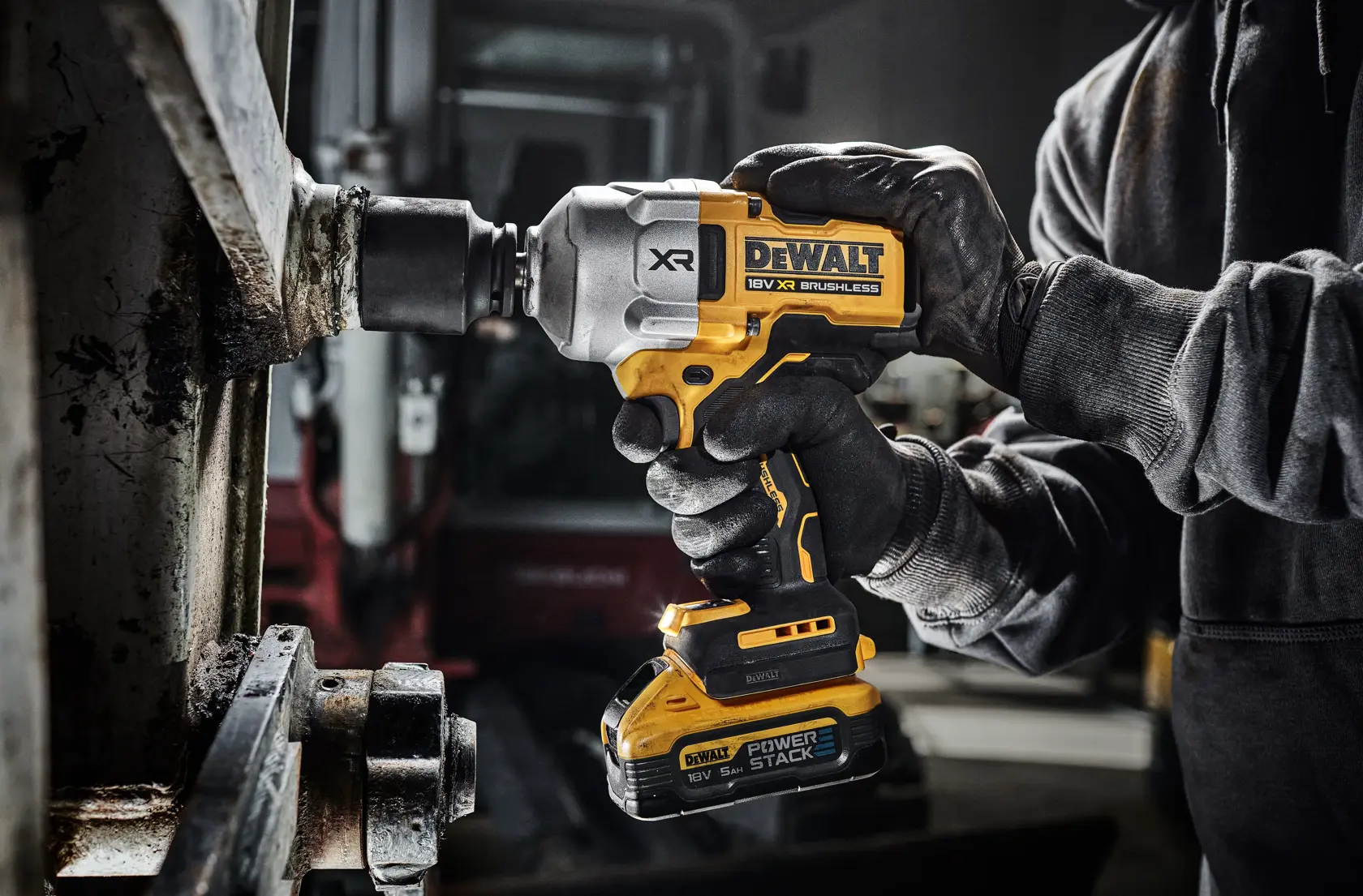Avvitatore a impulsi DEWALT senza fili usato da mani guantate su metallo in officina industriale.