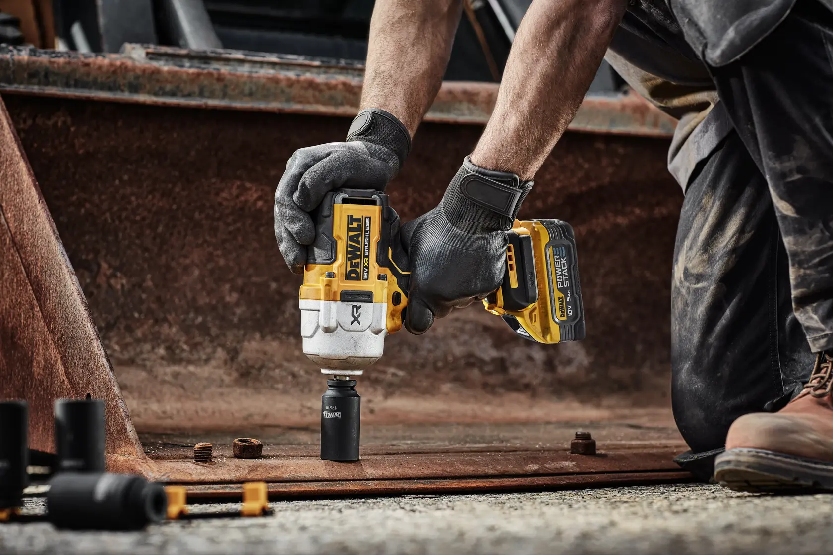 Chiave a impulsi DEWALT DCF961H2T usata su metallo arrugginito da una persona con guanti.