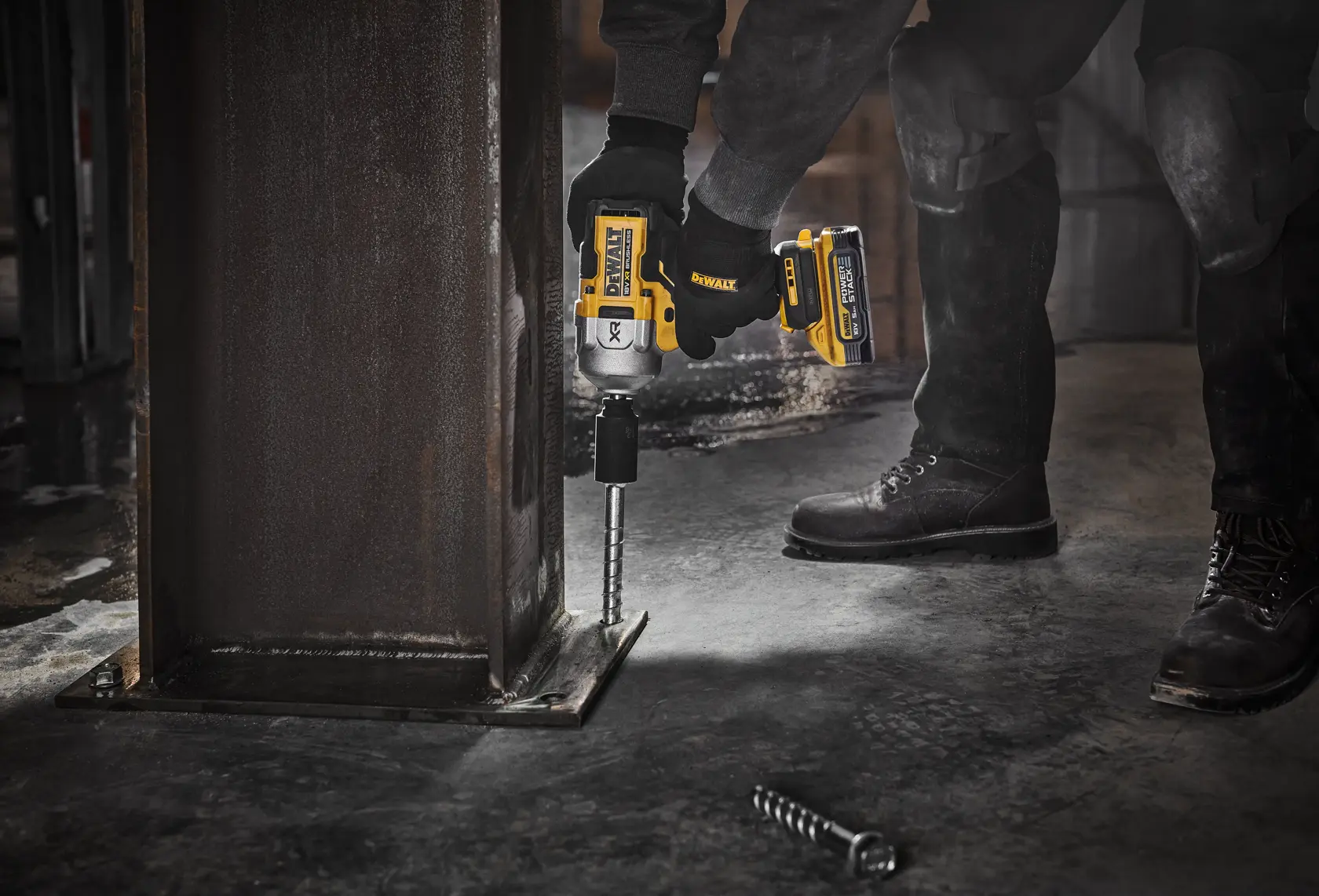 Persona usa avvitatore a impulsi DEWALT DCF961H2T su bullone di colonna d’acciaio in cantiere industriale.