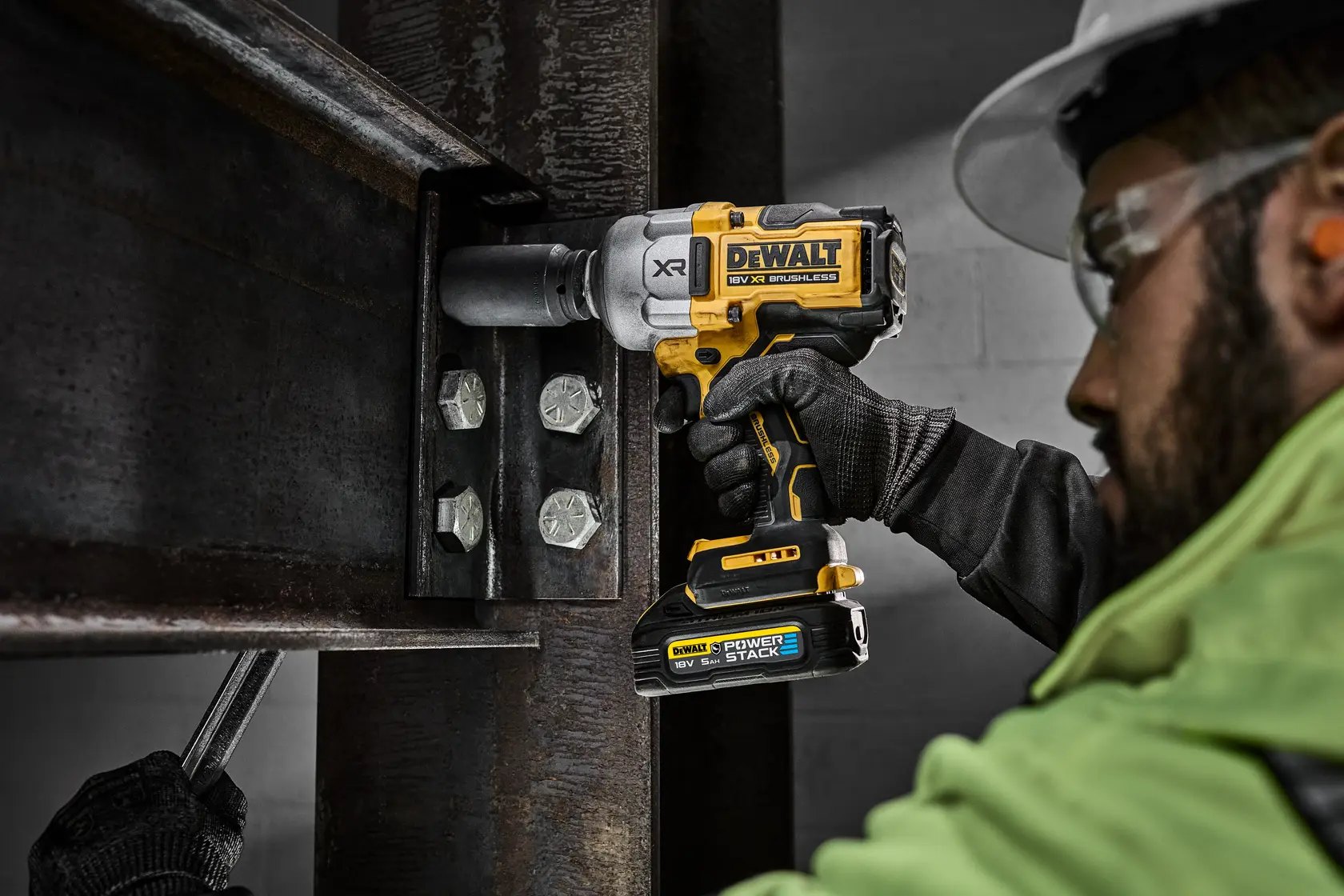 Worker uses a DEWALT XR impact wrench on steel beams at a construction site.