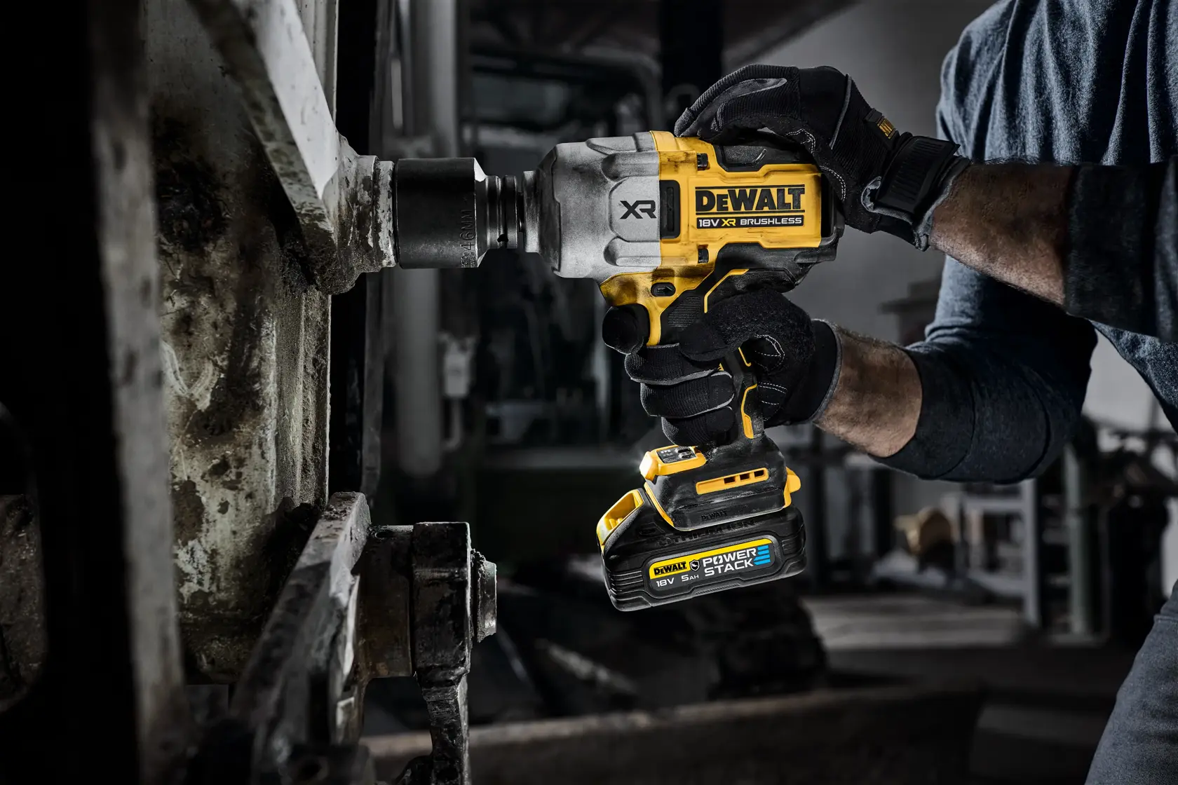 Photo of DEWALT DCF964NT cordless impact wrench in use, yellow and black tool, user wearing gloves.