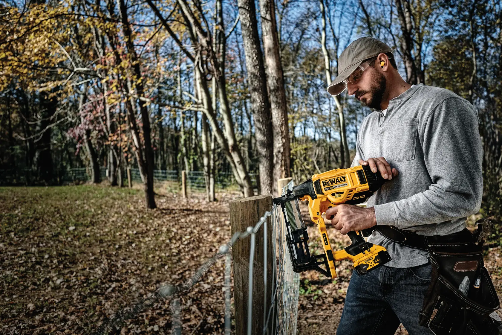 Una persona está utilizando una grapadora inalámbrica para cercas DEWALT (modelo DCFS950P2) para fijar una malla de alambre
