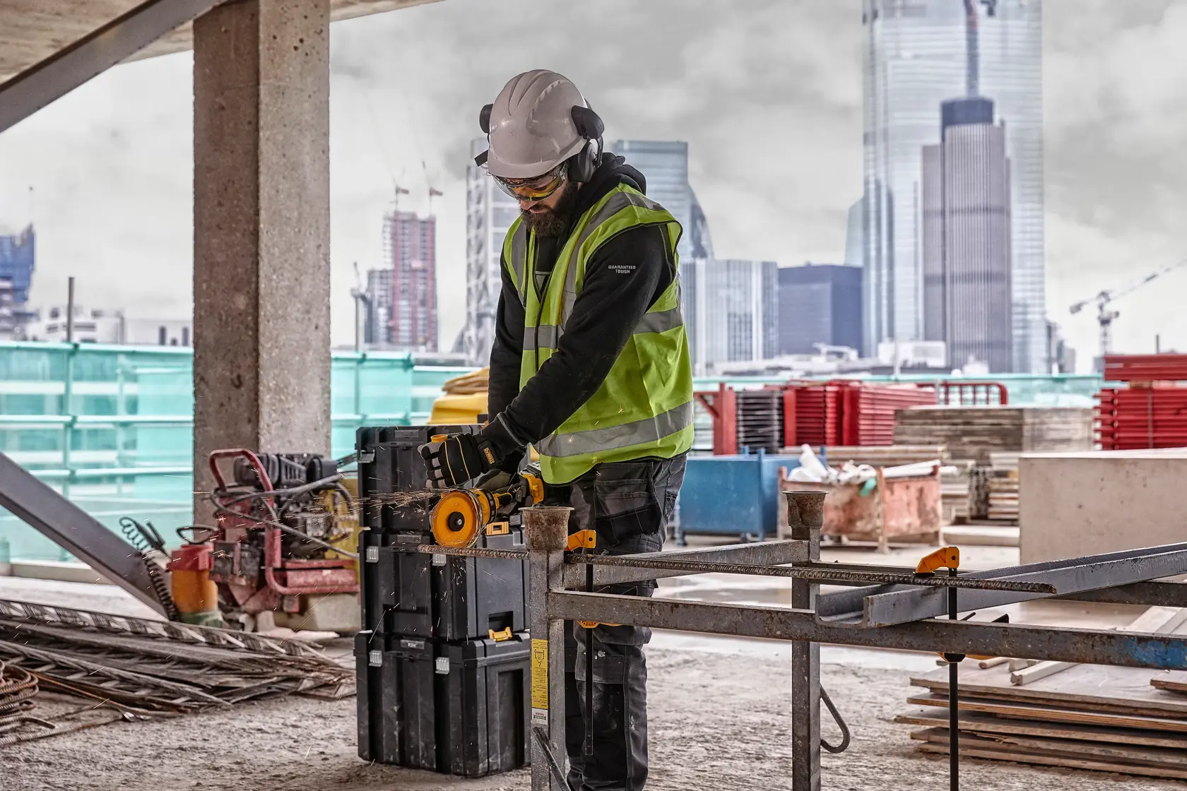 DEWALT tools DCZ507T2-XE, DCG418N, DCZ503X2-XE in use on construction site, worker cutting metal, urban backdrop.