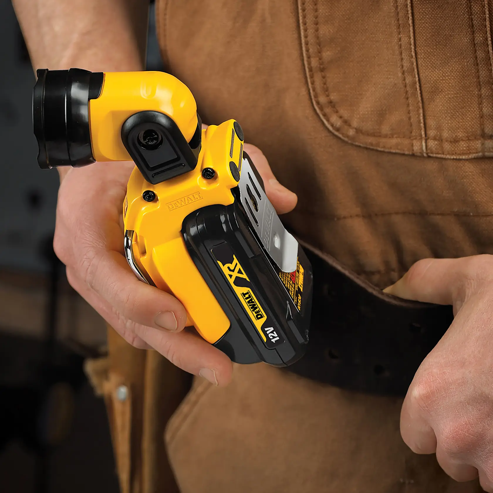 Mano sostiene una linterna DEWALT DCL510N 12V sujeta al cinturón de herramientas.