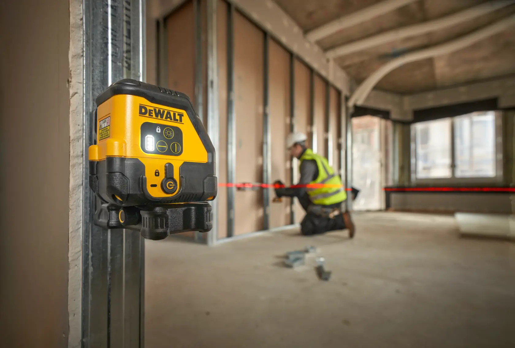 DEWALT-Laser-Wasserwaage am Metallrahmen. Arbeiter richtet Materialien mit rotem Laserstrahl aus.