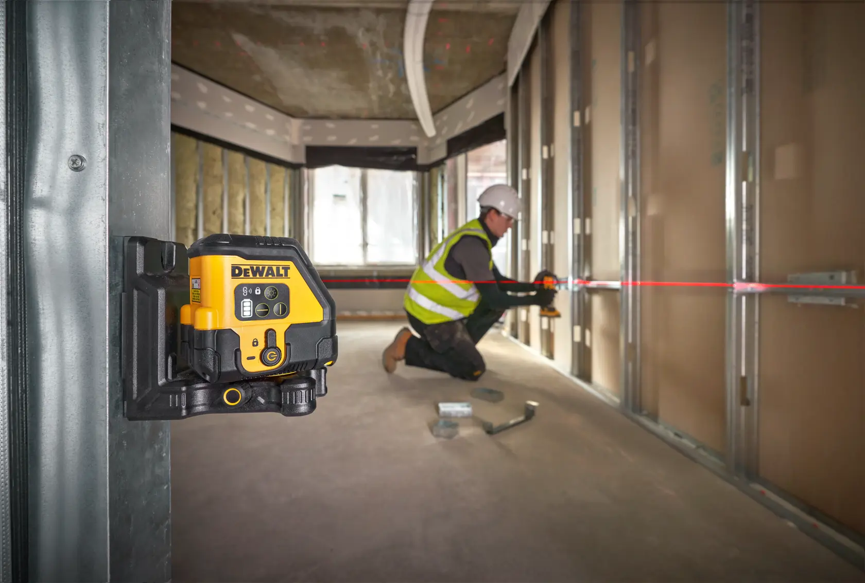 DEWALT Laser-Nivellierer montiert, Bauarbeiter richtet Metallrahmen mit rotem Laserstrahl aus.