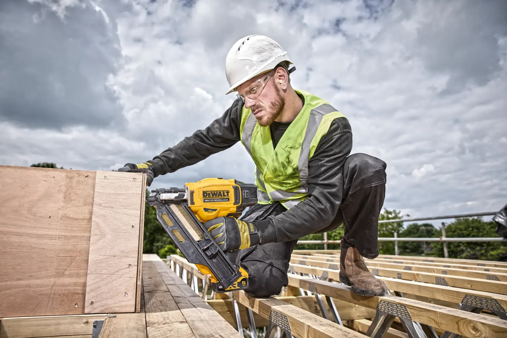 Trabajador utiliza la clavadora DEWALT DCN930P2 al aire libre, fijando madera en obra.