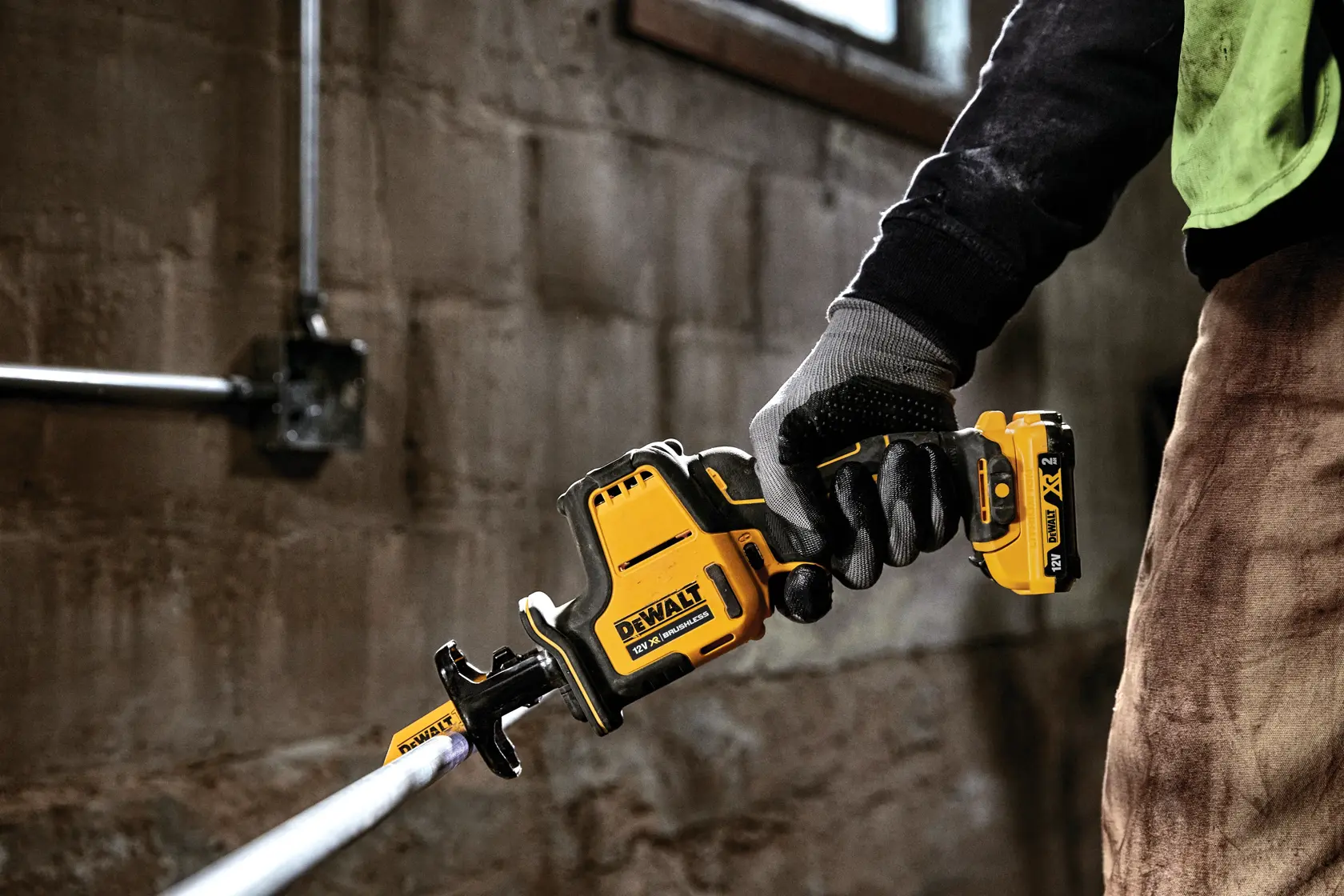 Persona usando una sierra recíproca inalámbrica DEWALT DCS312N para cortar una tubería en un taller.