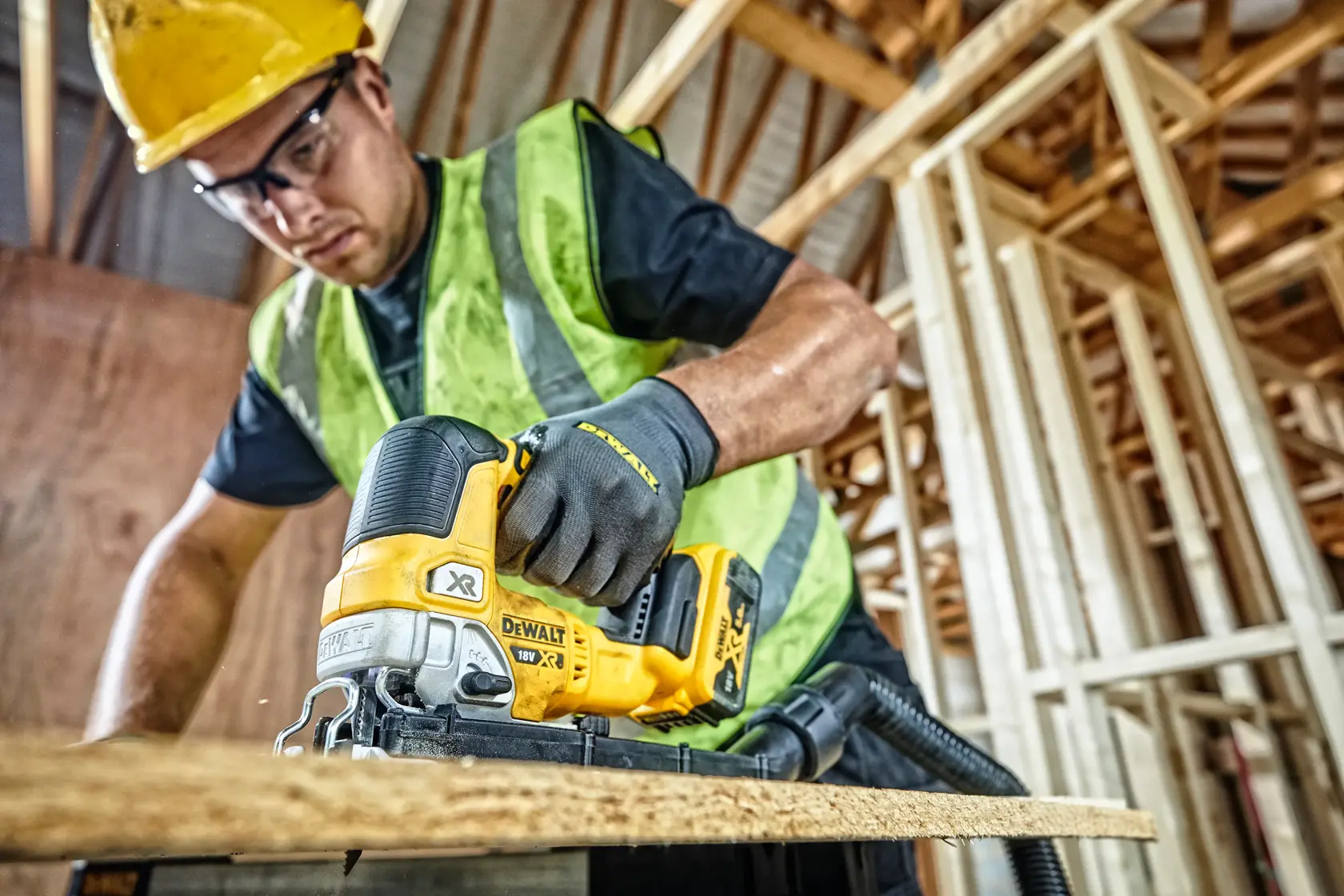 Sierra DEWALT DCS334P2 corta madera en obra, operario usando equipo de seguridad.