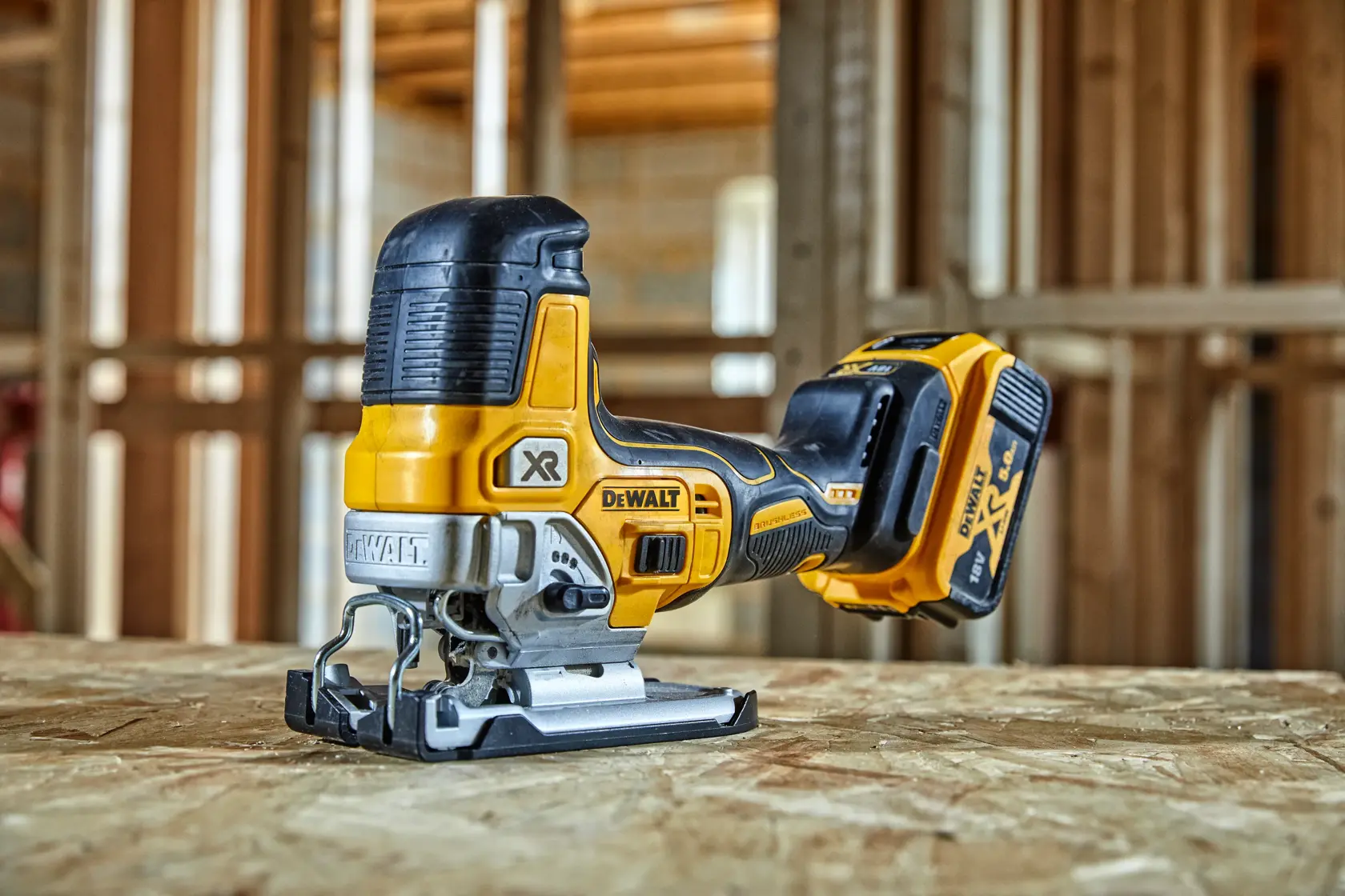 DEWALT cordless jigsaw, model DCS335P2, placed on a wooden surface at a construction site.
