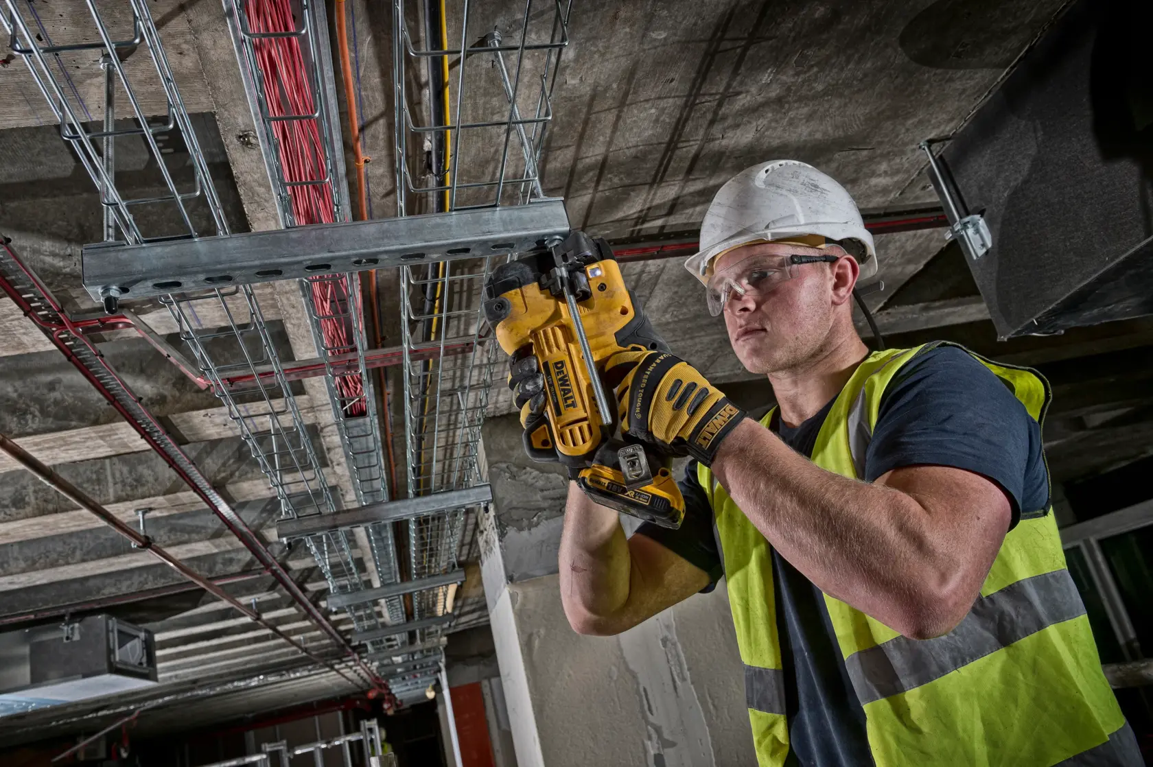 Arbeiter schneidet mit DEWALT DCS350NT Metallrohr an einer Deckeninstallation.