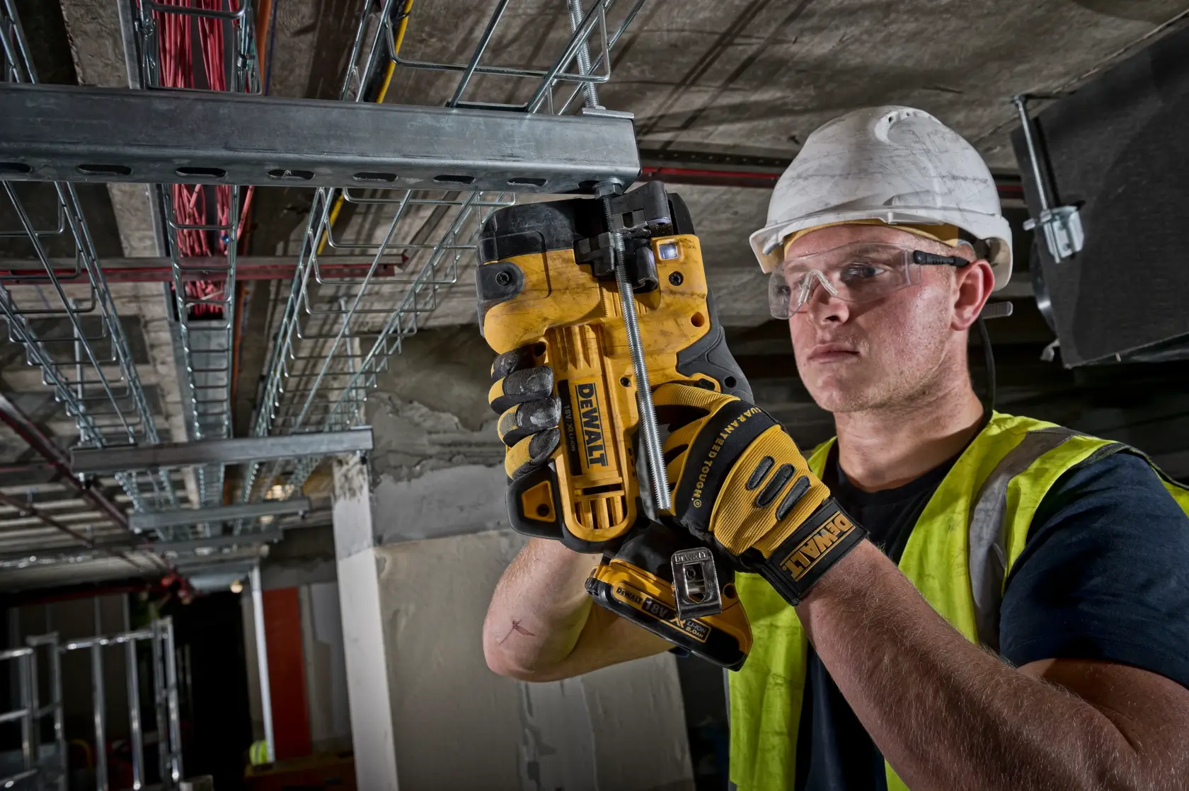 Arbeiter schneidet Metallrohr mit DEWALT DCS350NT, trägt Handschuhe und Sicherheitsausrüstung.