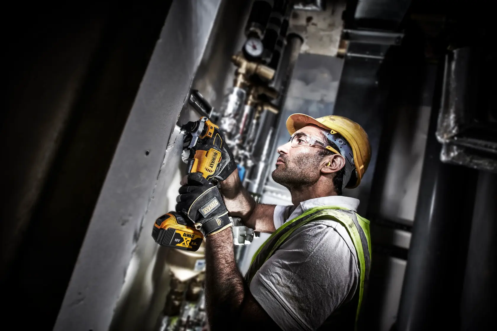 Trabajador usando herramienta inalámbrica DEWALT DCS356P2 para cortar material de pared en entorno industrial.