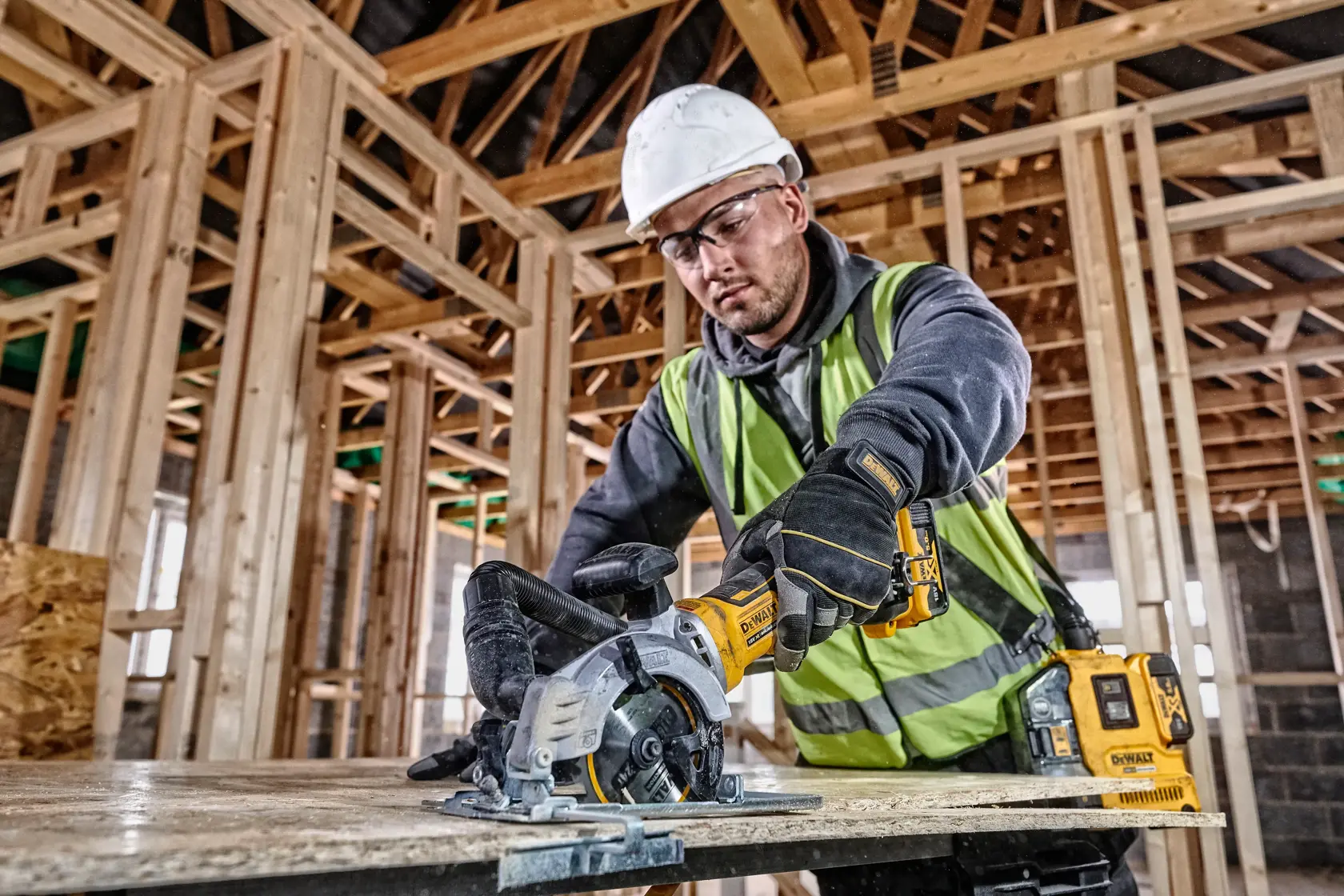 DEWALT DCS571NT-XJ y DCS571NT usados por trabajador cortando madera en obra. Categoría fotografía.