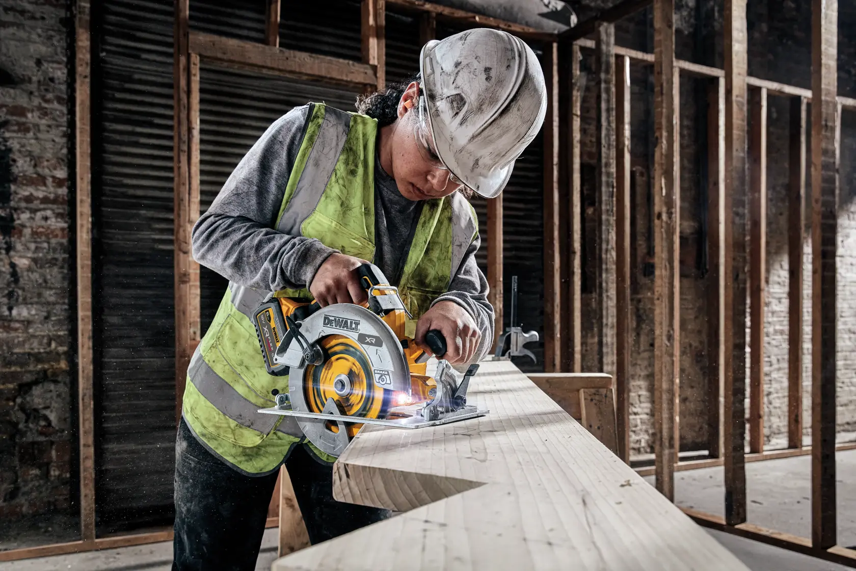Operaio taglia il legno con sega circolare DEWALT in cantiere. Gilet e casco di sicurezza.