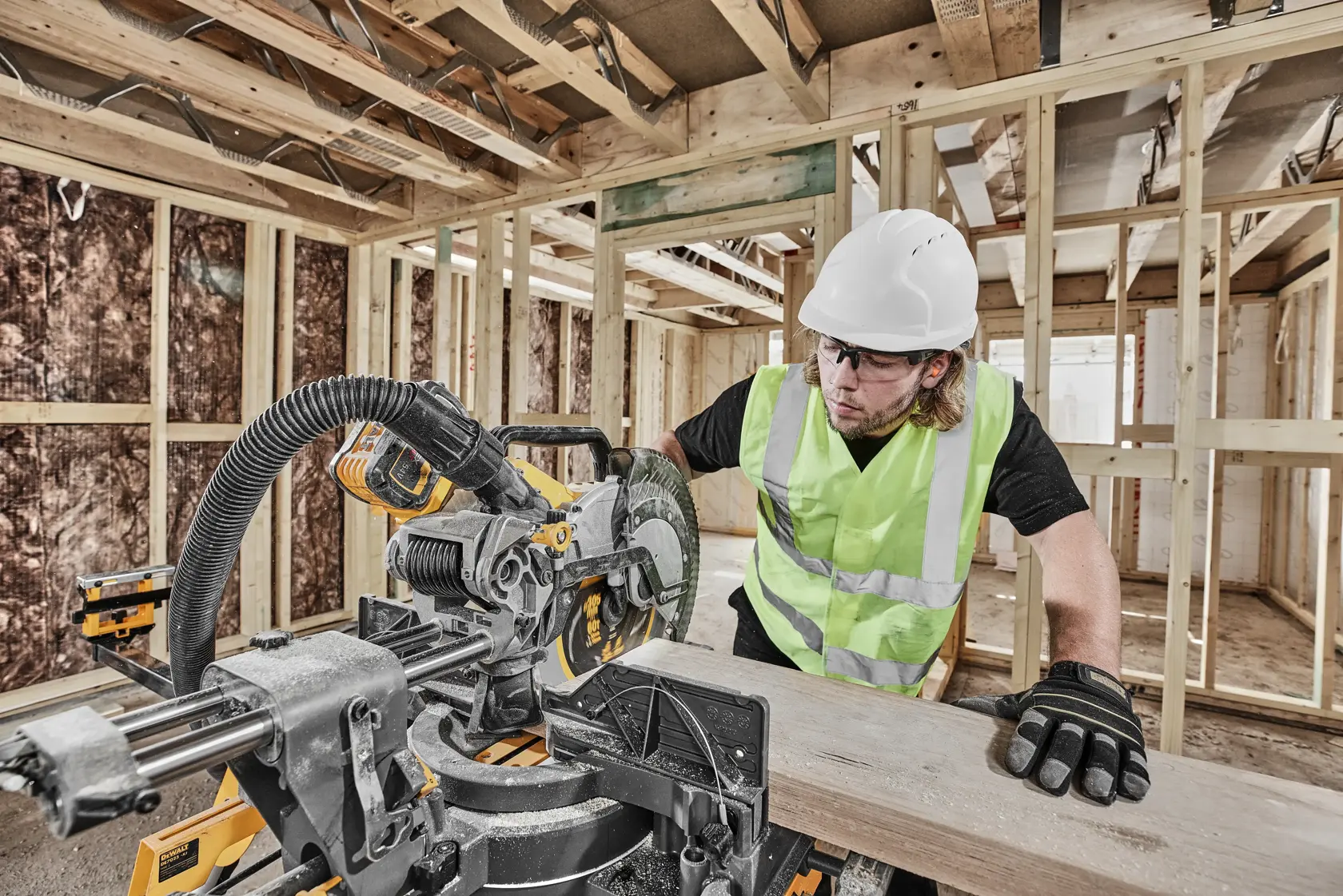 DEWALT DCS781X2-QW, DCS781X2 Säge im Einsatz auf Baustelle. Arbeiter sägt Holz mit Schutzausrüstung.