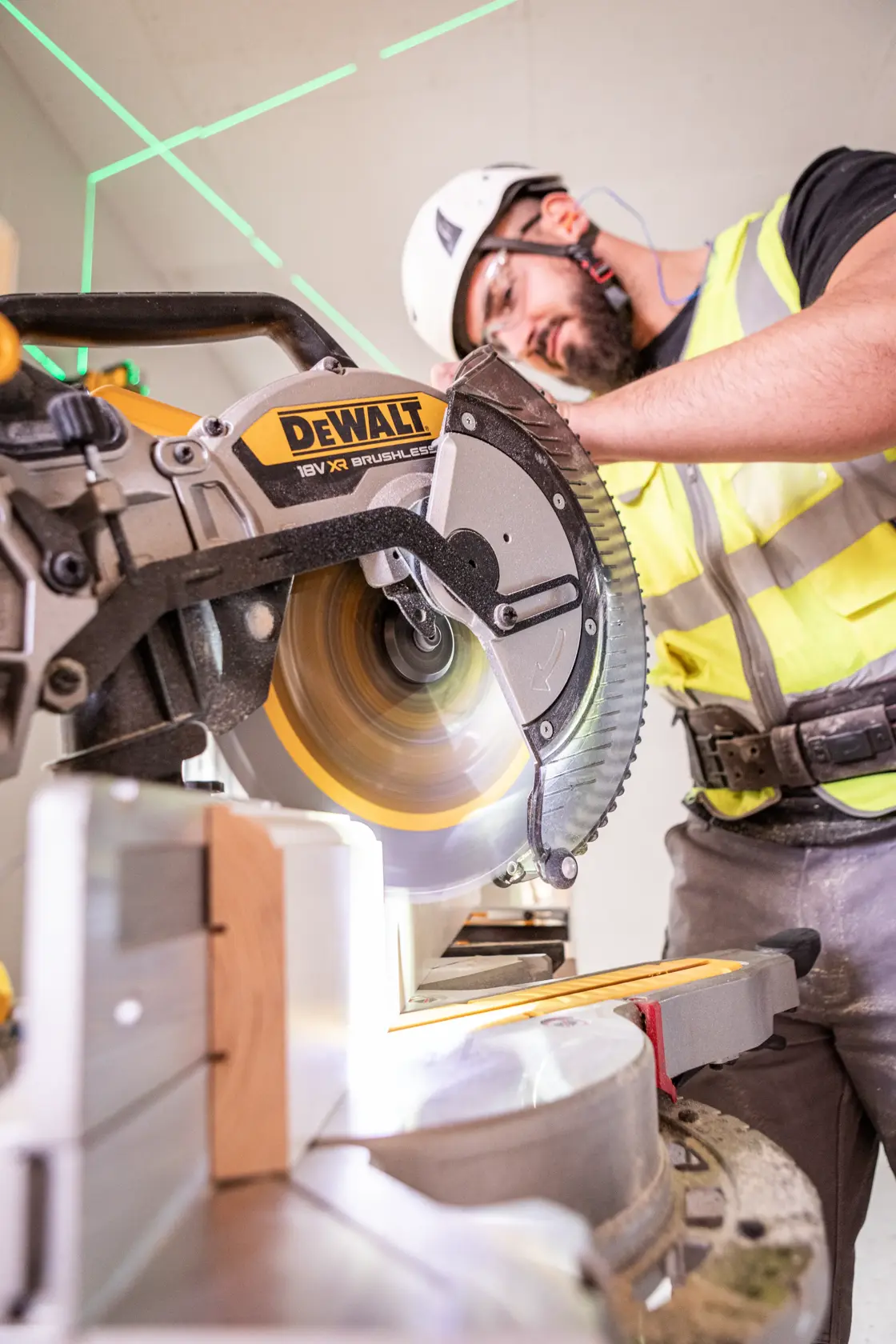Persona usando sierra de inglete DEWALT para cortar madera, con equipo de seguridad.