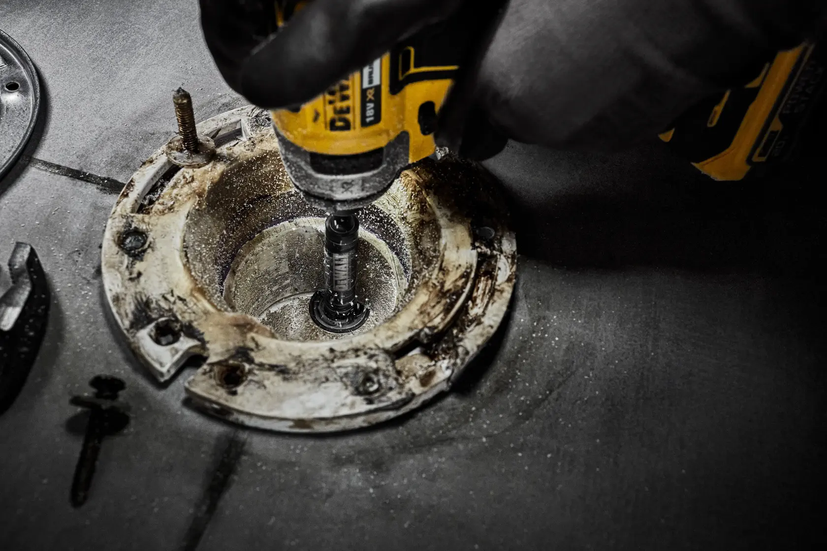 Herramienta DEWALT perforando o lijando dentro de una base metálica circular sobre una superficie de trabajo.