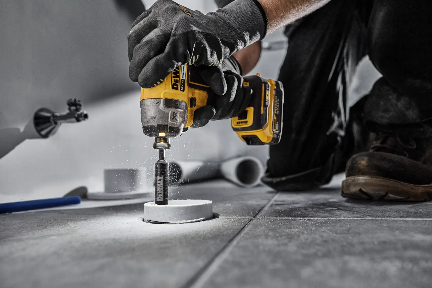 DEWALT DT20563 perforando una baldosa. El operario usa guantes para protección.