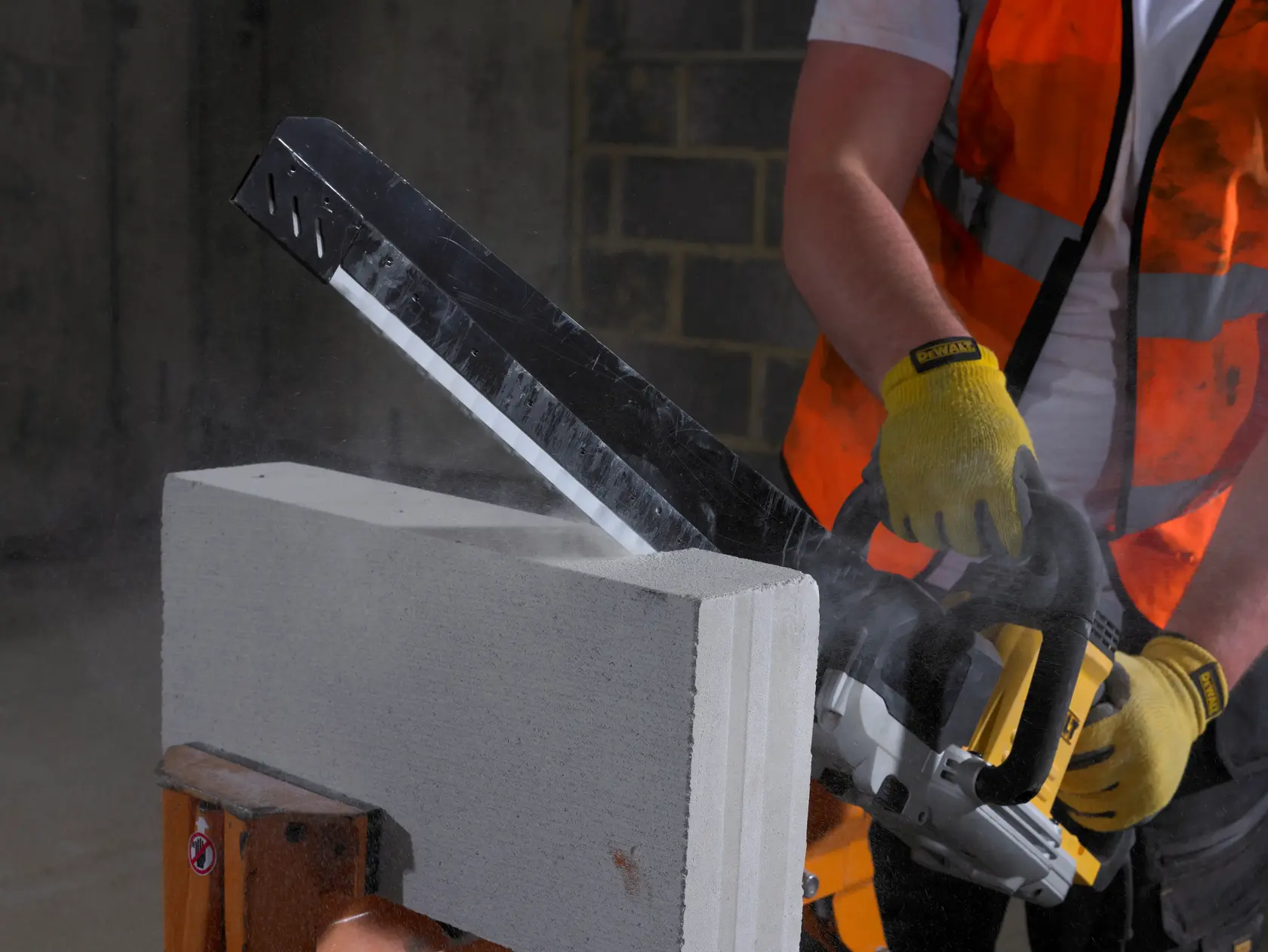 Arbeiter schneidet Betonblock mit DEWALT Säge, trägt Handschuhe und Sicherheitsweste.